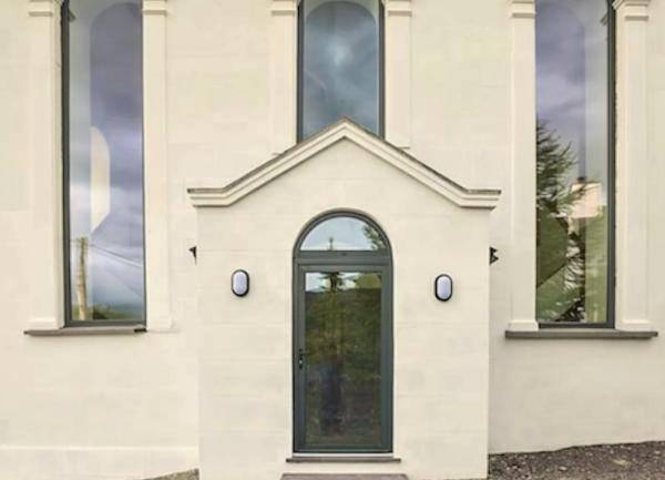 A covered porch flanked by tall double height windows on the house wall.