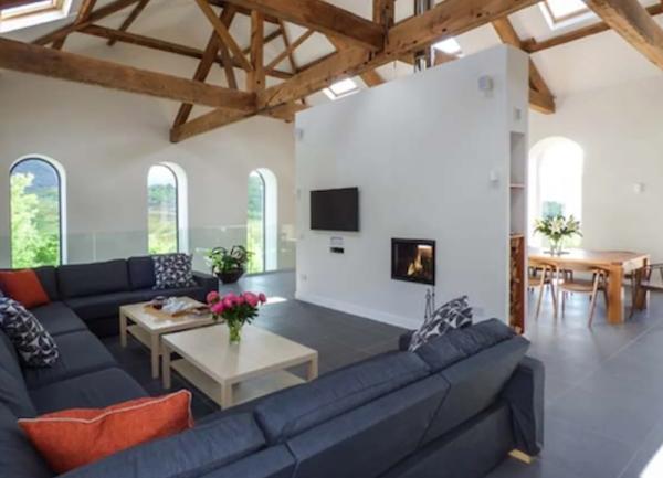 A lounge with a large c-shaped sofa, coffee tables and a TV.