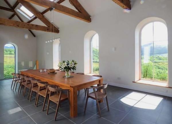 A dining area with a long wooden table with 16 chairs.