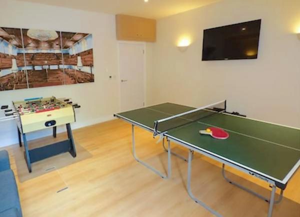 A games room with table tennis table, table football and a TV.
