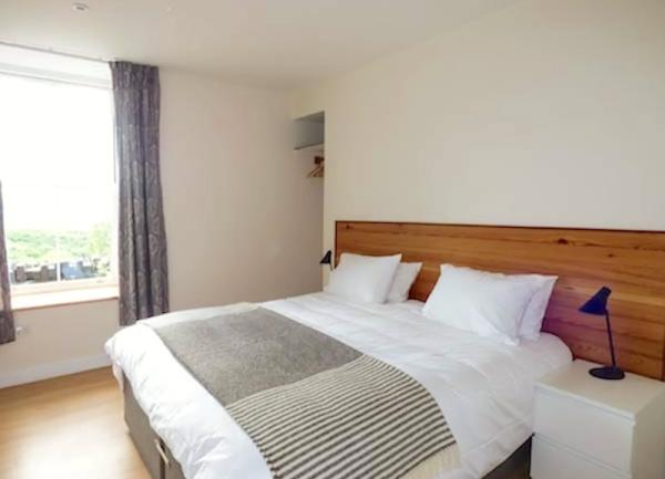 A double bedroom with a bed, bedside cabinet and table lamp.