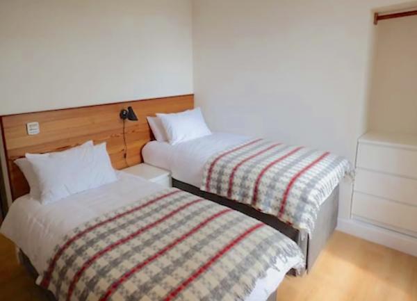 A twin bedroom with two single beds and a wall-mounted reading light.