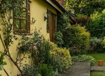 Paved path to a front door through a shrub-filled garden and a lawn.