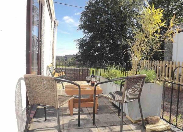 Garden patio ith a wooden table and four outdoor chairs.