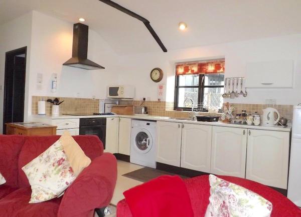 kitchen area with fitted cupboards, oven, washing machine and small appliances on worktops.