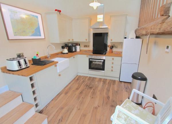 Kitchen with fitted cupboard, oven, fridge freezer and highchair.