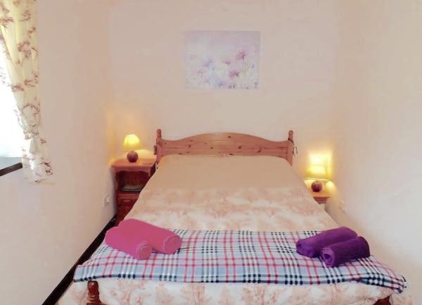 Double bedroom with bed, bedside cabinets with table lamps and towel sets.