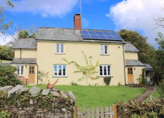 A country cottage overlooks a walled lawn garden.
