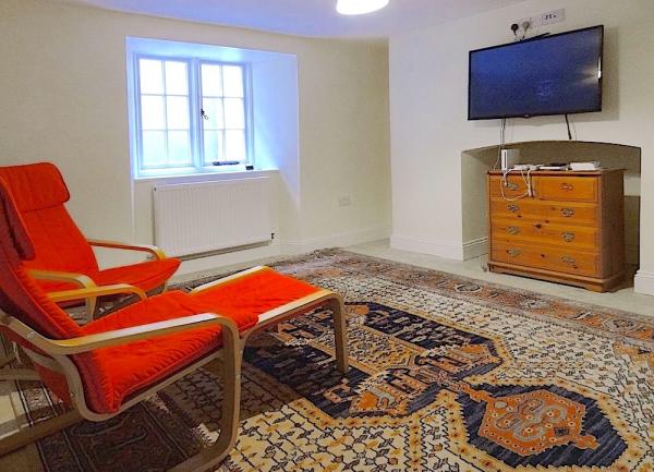 TV Room with widescreen TV, armchairs and chest of drawers.