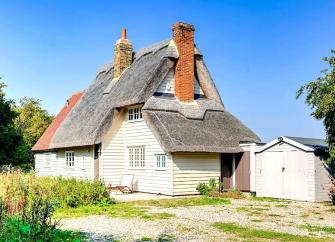 A clapperboard thatched holiday cottage and garden in Essex.