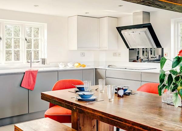 Kitchen diner with oven, fitted cupboards and wood dining table.