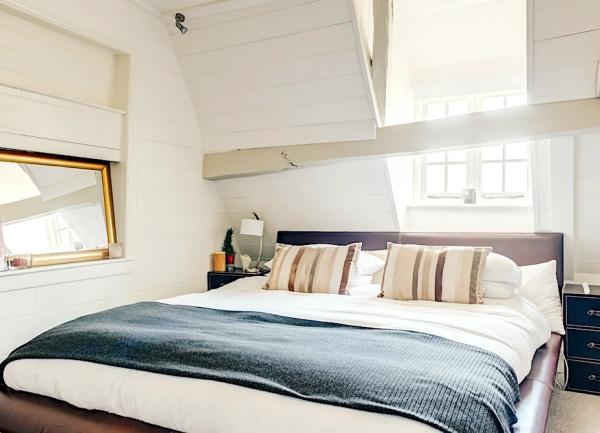 Double bedroom with bed, bedside cabinets, table lamps and large mirror.