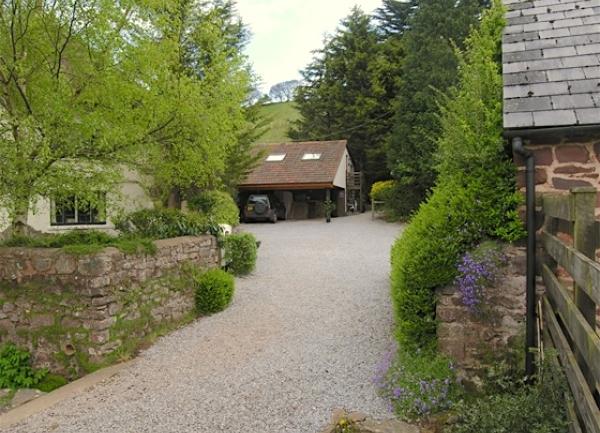 Stone walls mark the entrance to a tree-lined drive to two cottages.