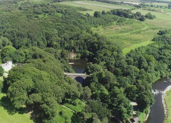Tree-lined wooded valley with winding river.