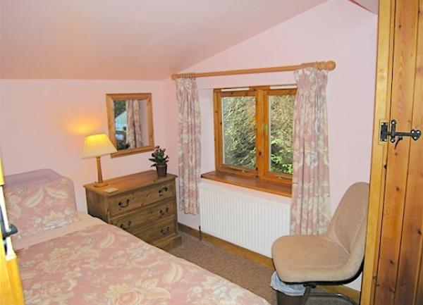 Single bedroom with bed, chest-of-drawers and bedside chair.