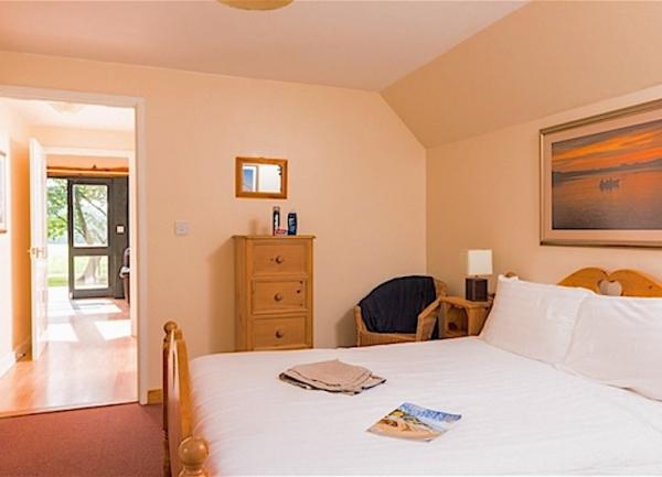 Double bedroom wit bed, chest-of-drawers, chair and bedside lights.