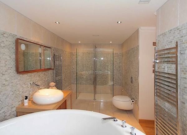 Tiled bathroom with shower, sink, bath and bidet.