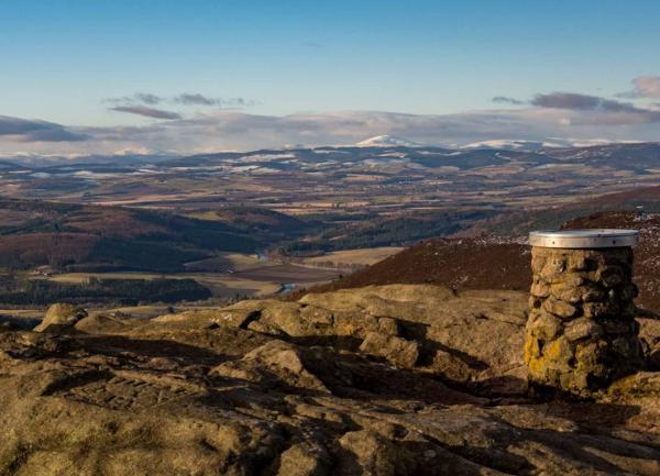 Far reaching moorland views with a summit cairn in foreground.
