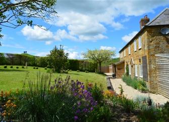 Side view of a long farmhouse and large lawn.