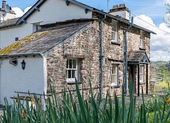 Front exterior of a stone-built countryside house and garden.