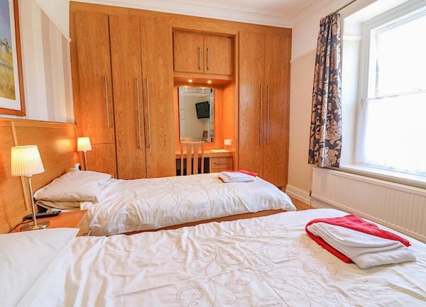 Twin bedroom with beds, bedside lights and fitted wardrobe.