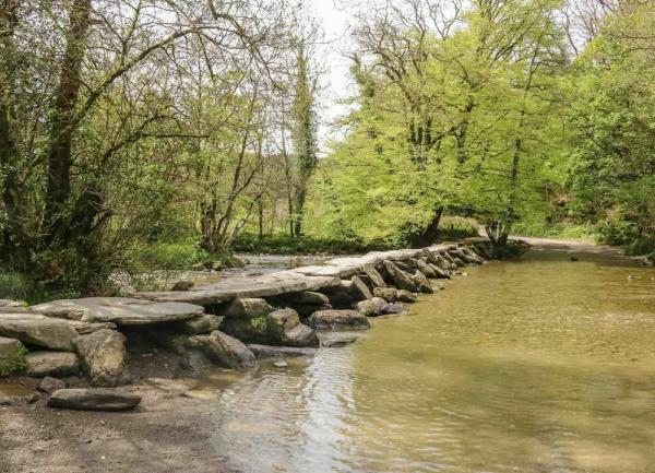 Tarr Steps - clapper bridge cross a wide, tree-lined river.
