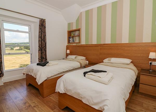 Twin bedroom with beds and rural views through a sash window.