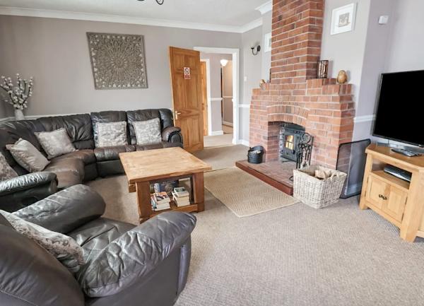 Lounge with wrap-around sofa, armchairs, TV and fireplace.