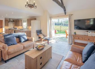 Lounge with French windows, widescreen TV and sofas.