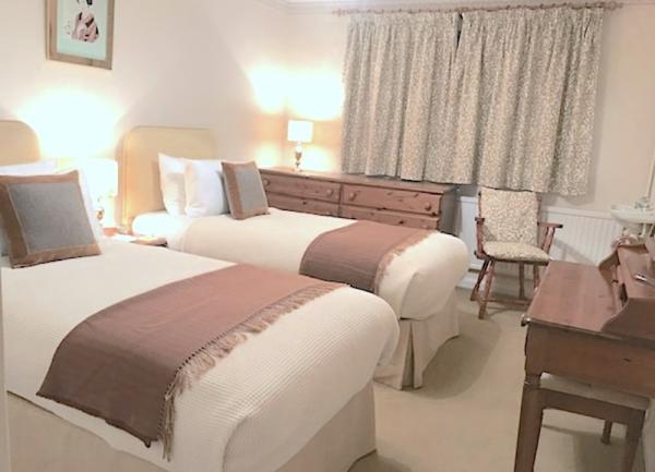 Twin bedroom with beds, dressing table, chest-of-drawers and armchair.