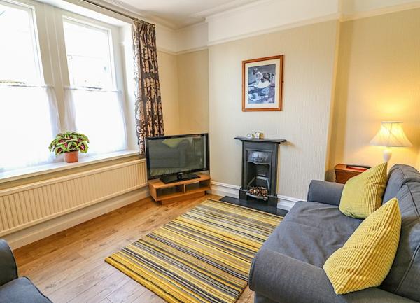 Snug lounge with TV, armchair and sofa.
