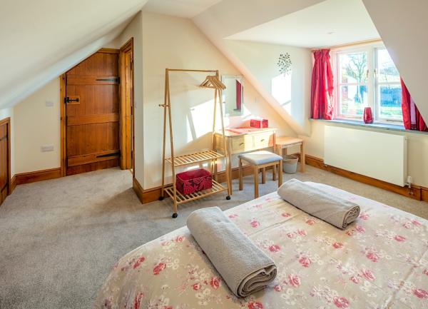 Double bedroom with bed, clothes hanger and chest of drawers.