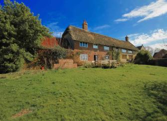Large thatched farmhouse overlooks a spacious lawn