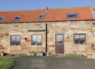 Stone built Whitby holiday home with terracotta tiles and Velux windows on the roof overlook a lawn and parking space