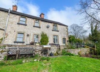 Large stone-built rural cottage exterior with a spacious lawn.