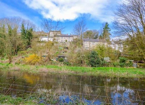 Beyond a river are a cluster of stone cottages.