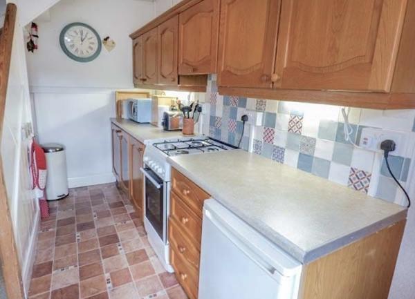 Galley-style kitchen with fridge and cooker.