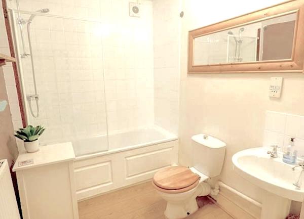 Bathroom with bath/shower, wash basin and toilet.