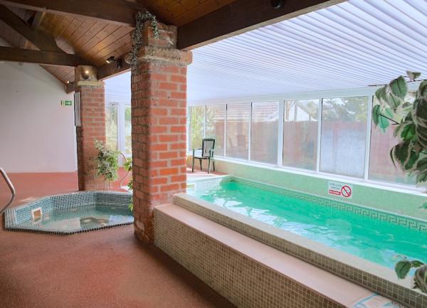 An indoor heated pool and hot tub. Floor-to-ceiling windows line one side.