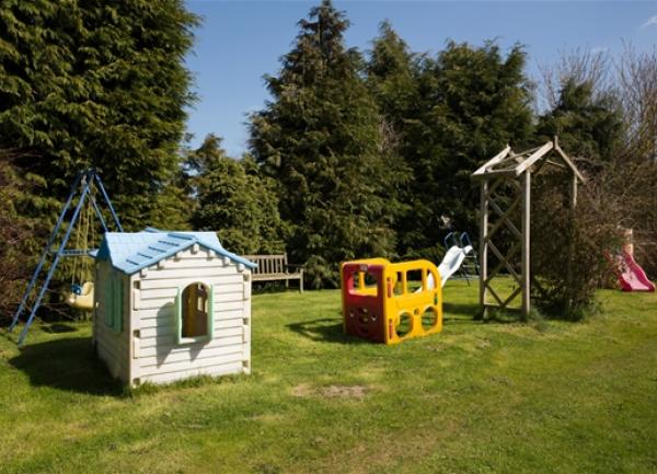 Children's play ares with a slide, swing, climbing frame and a Wendy house.
