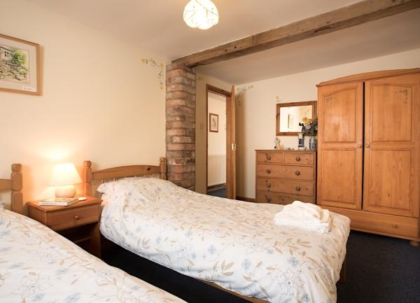 Twin bedroom with beds, bedside table with table lamp, wardrobe and chest of drawers.