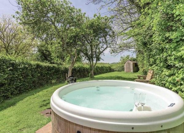S hot tub on a small patio in a long, lawn-covered country garden.