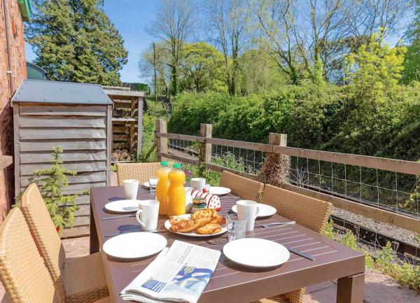 An outdoor table laid  with tea plates and cakes stands on a country terrace.terrace