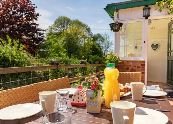 A fenced patio with a table laid for tea opposite a heritage railway line.