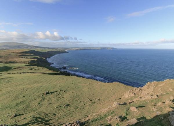 A curving Somerset coastline with open fields and small cliffs descending into the sea.
