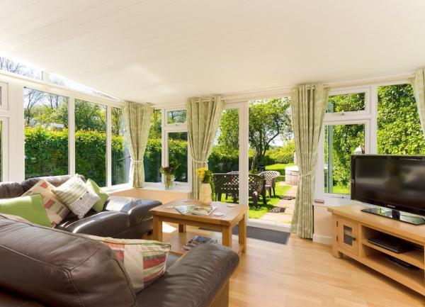 A lounge- with floor-to-ceiling windows opening onto a garden, featuring squashy leather sofas and widescreen TV.ng