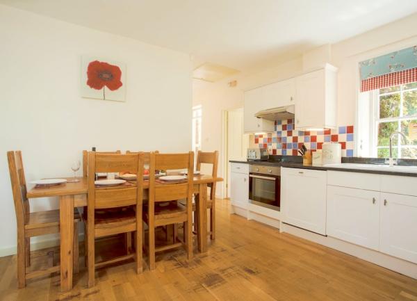 A dining table and chairs adjoining a kitchen laid for breakfast.