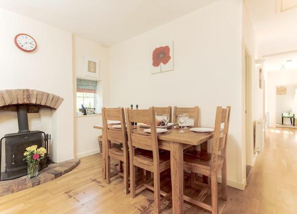 A dining table and chairs adjoining a kitchen is laid for tea.