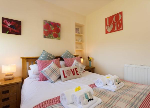 A double bedroom with a bed with many cushions and twin bedside cabinets with table light.