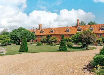 A terraced row of Norfolk cottages with flower-filled front gardens.